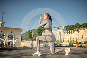 Young female sportsperson in grey sportswear doing squats