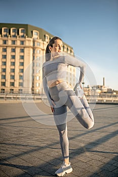 Young female sportsperson stretching her legs and looking concentrated