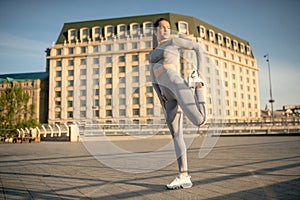 Young female sportsperson stretching her legs and looking concentrated