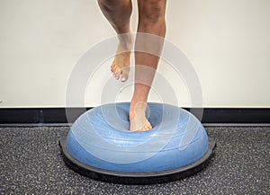Young female standing on a bosu ball for a workout