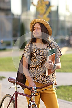 Young female student with backpack and books riding a retro bicycle. Female on retro bicycle.