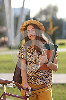Young female student with backpack and books riding a retro bicycle. Female on retro bicycle.