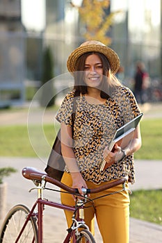 Young female student with backpack and books riding a retro bicycle. Female on retro bicycle.