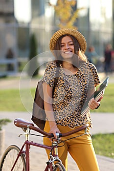 Young female student with backpack and books riding a retro bicycle. Female on retro bicycle.
