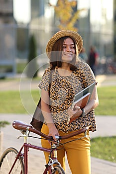 Young female student with backpack and books riding a retro bicycle. Female on retro bicycle.