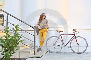 Young female student with backpack and books riding a retro bicycle.