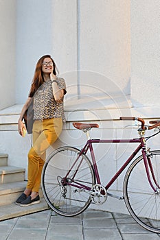 Young female student with backpack and books riding a retro bicycle.