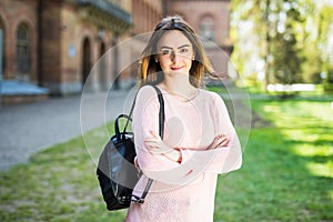 Young female student with backpack walking in the campus park