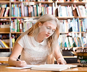 Young female student doing assignments in library photo