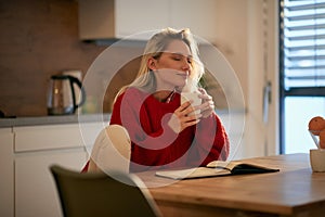 A young female student enjoying coffee smell at the kitchen. Routine, student, morning