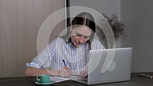 Young female student in headphones studying at home, online education.