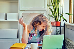 young female student with laptop and cup of coffee studying at home