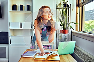 young female student with laptop and cup of coffee studying at home