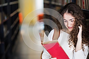 Young female student in library, focusing on final project, presentation. University student preparing for final exam.