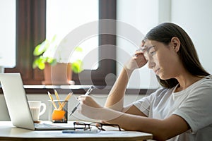 Young female student preparing exams on laptop at home