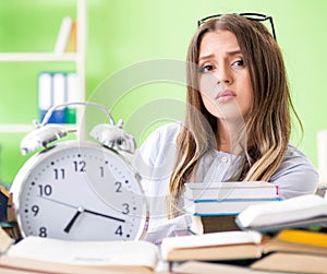 Young female student preparing for exams with many books in time