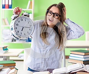 Young female student preparing for exams with many books in time