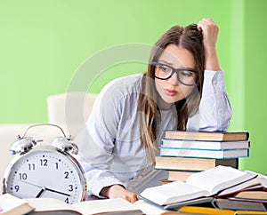 Young female student preparing for exams with many books in time