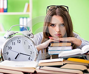 Young female student preparing for exams with many books in time