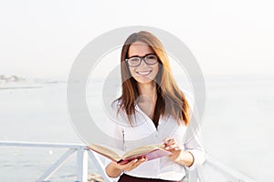 Young female student in reading glasses with the book