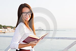 Young female student in reading glasses with the book