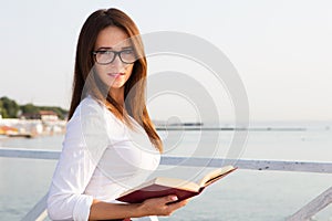 Young female student in reading glasses with the book