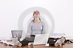 Young female student sitting on the floor surrounded by books and clutter. photo