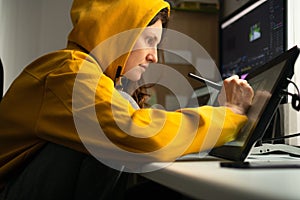 A young female student sitting at the table, using graphics tablet. Woman working from home. Concept for distance