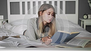 Young female student studying at home, online education. Young woman reads a book