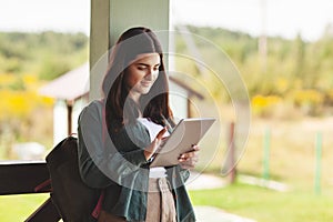 Young female student studying using tablet in college or private school outdoors, technology learning concept. Technology,