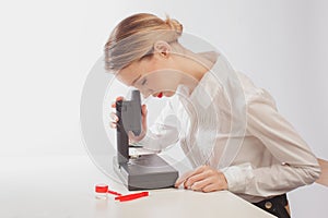 Young female student using microscope in science lab