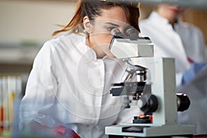 A young female student using a microscope in a laboratory. Science, chemistry, lab, people