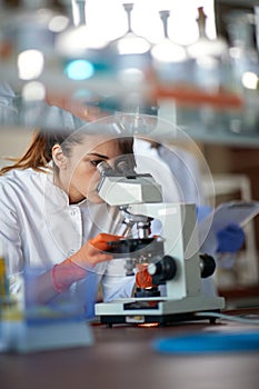 A young female student working with a microscope in a laboratory. Science, chemistry, lab, people