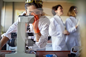 Young female student working at the microscope in the university laboratory. Science, chemistry, lab, people