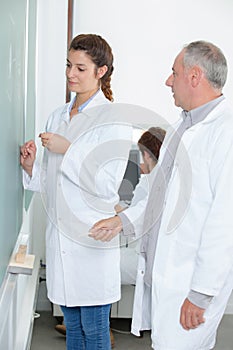 young female student write chemical formula on blackboard