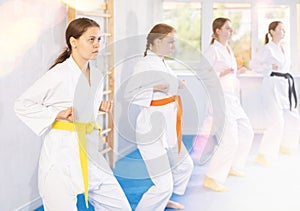 Young female students repeat position and perform sequence of punches and painful techniques kata