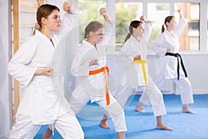 Young female students repeat position and perform sequence of punches and painful techniques kata