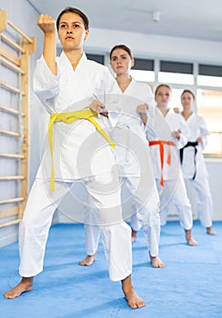 Young female students repeat position and perform sequence of punches and painful techniques kata