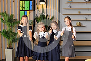 Young female students in school uniforms before the lesson in the classroom.