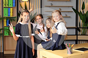 Young female students in school uniforms before the lesson in the classroom.