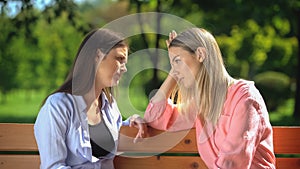 Young female supporting and comforting friend sitting park bench, depression