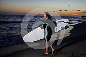 Young female surfer on beach in sunset