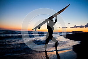 Young female surfer on beach in sunset