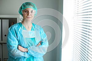 Young female surgeon doctor standing with arms crossed and smiling at hospital.