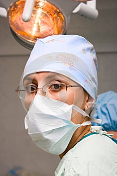 Young female surgeon with mask in operation room