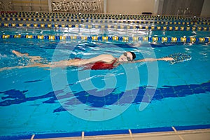 Young female swimmer is performing sidestroke in pool