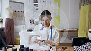 Young female tailor working on sewing machine in the sew studio.