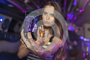 Young female taking a selfie in a limousine