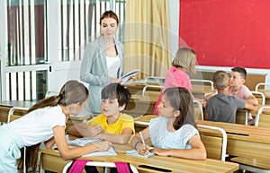 Female teacher controlling group work of interested tweens at lesson