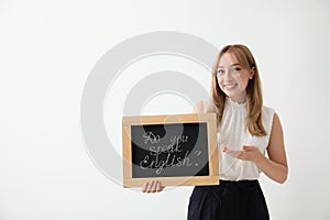 Young female teacher holding chalkboard with words DO YOU SPEAK ENGLISH? on light background. Space for text